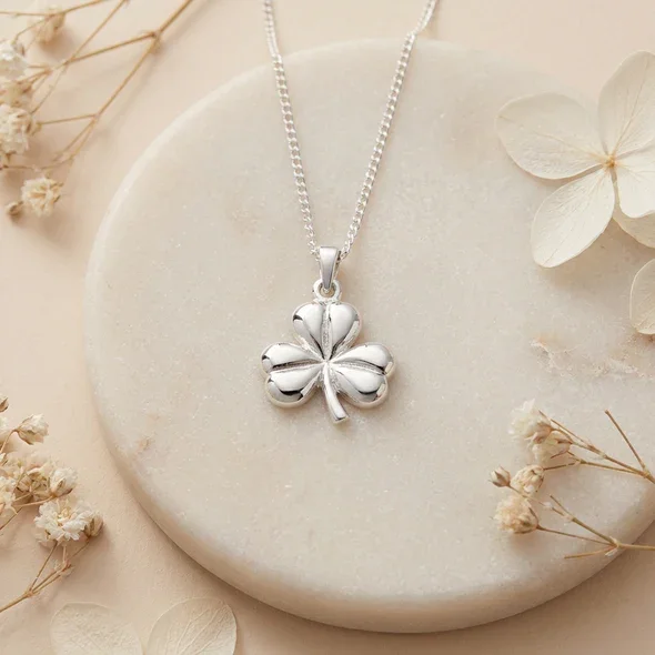 Sterling Silver Irish Shamrock Pendant, sculpted three-lobe form, high mirror polish, shown on sea stone with dried botanicals