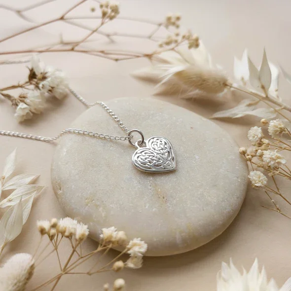 Sterling Silver Celtic Heart Knotwork Pendant, mirrored interlaced interior, high mirror polish, shown on sea stone with dried botanicals