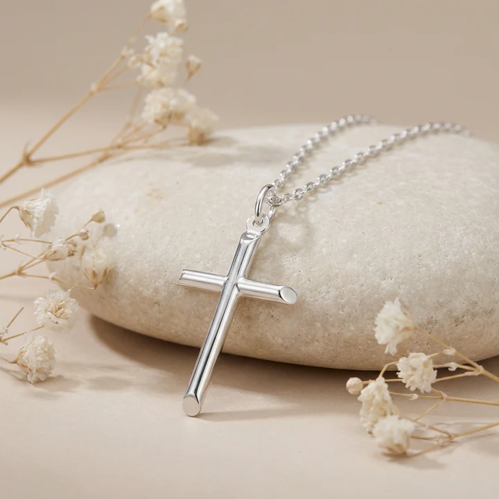 Sterling Silver plain cross pendant, round tubular arms, shown on sea stones with dried botanicals