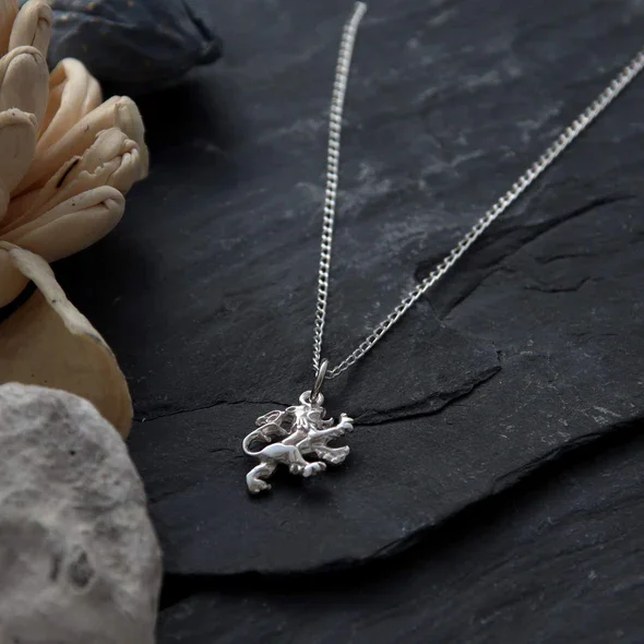 Sterling Silver Scottish Lion Rampant Pendant, sculpted heraldic form, engraved detail, shown on Scottish slate with sea stones and dried botanicals