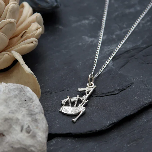 Sterling Silver Scottish Bagpipes Pendant, large format, fanned drone arrangement, fringe detail, shown on Scottish slate with sea stone and dried botanicals