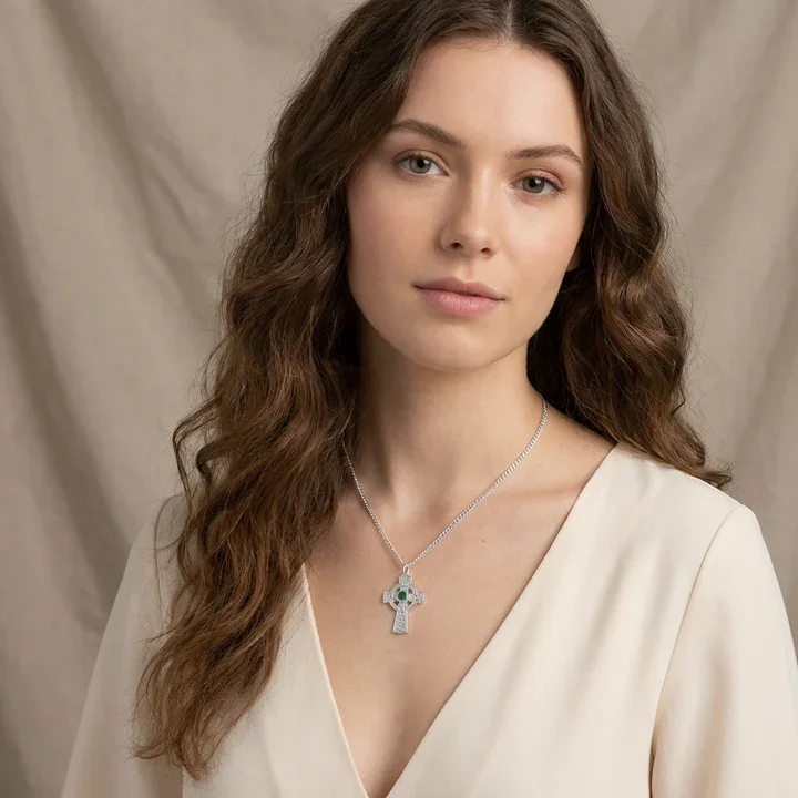 Sterling Silver Celtic cross pendant with green cubic zirconia, shown on model at neckline giving scale