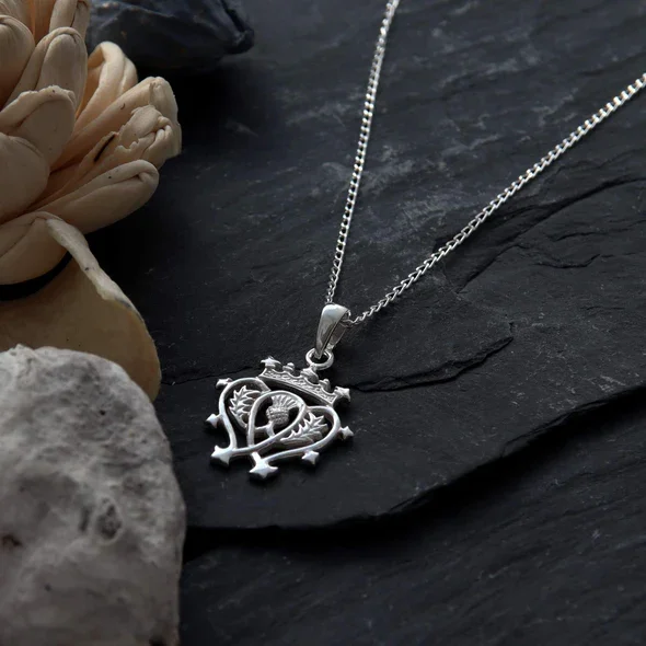 Sterling Silver Scottish Luckenbooth Pendant, thistle integrated heart form, crowned, shown on Scottish slate with sea stones and dried botanicals