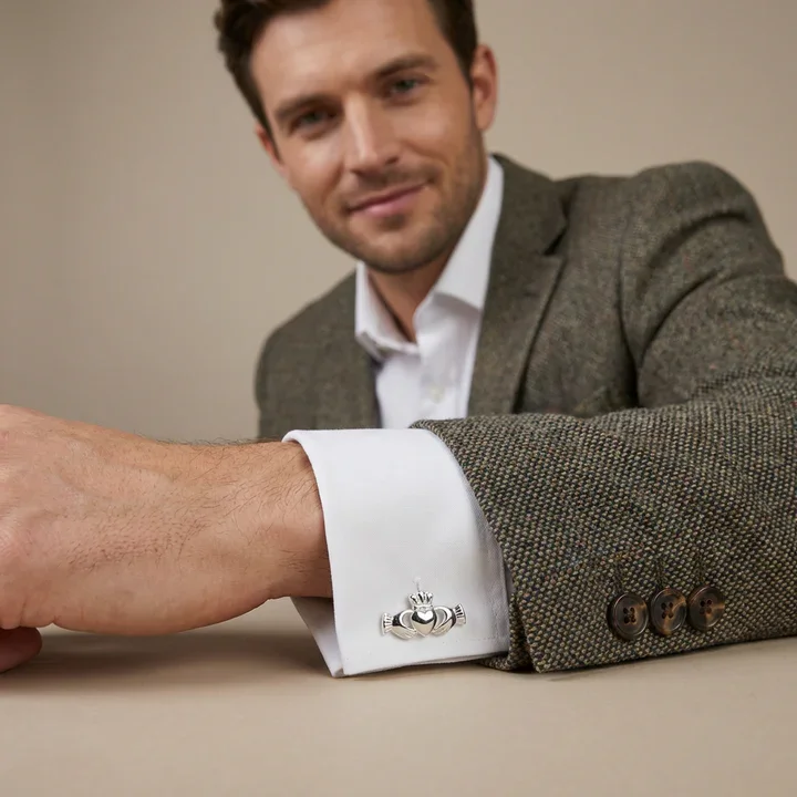 Sterling Silver Claddagh cufflinks. Sculptural hands, ribbed cuffs, crowned heart, high mirror polish, shown on model at cuff giving scale