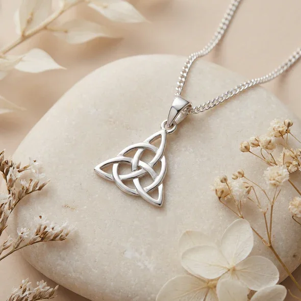 Sterling Silver Celtic Trinity Knot Pendant, triquetra design, high mirror polish, shown on sea stones with dried botanicals