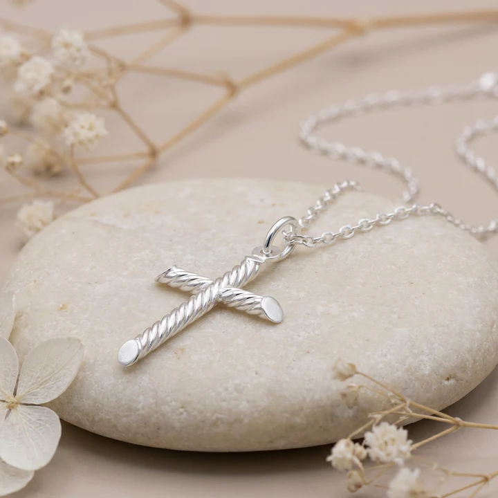 Sterling Silver cross pendant, rope twist tubular arms, displayed on sea stone with dried botanicals