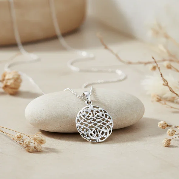 Sterling Silver Celtic Knotwork Disc Pendant, all-over interlaced plaitwork, high mirror polish, shown on sea stone with dried botanicals