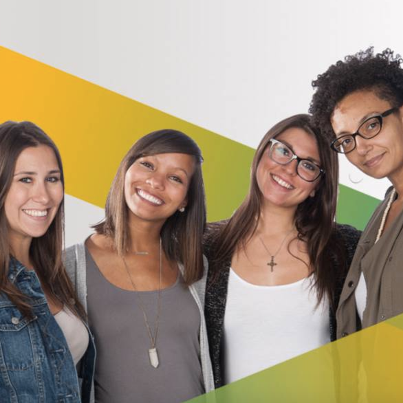 Four women smiling and standing together in front of a white wall with yellow and green geometric shapes.