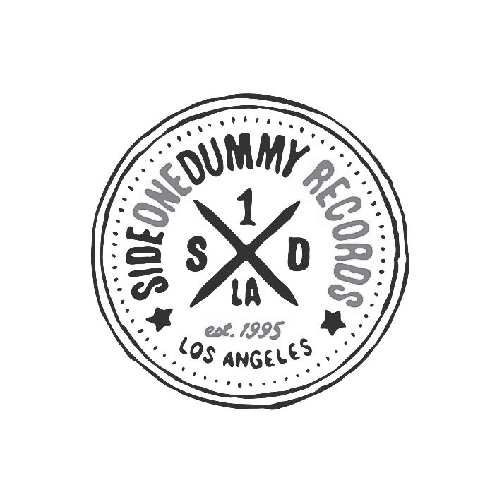 A circular logo with text and graphic elements. The center has a crossed design with the numbers 1 and LA, and the letters S and D. Surrounding the center, the text reads 'Sideshow Dummy Records' at the top and bottom, with 'est. 1995' and 'Los Angel