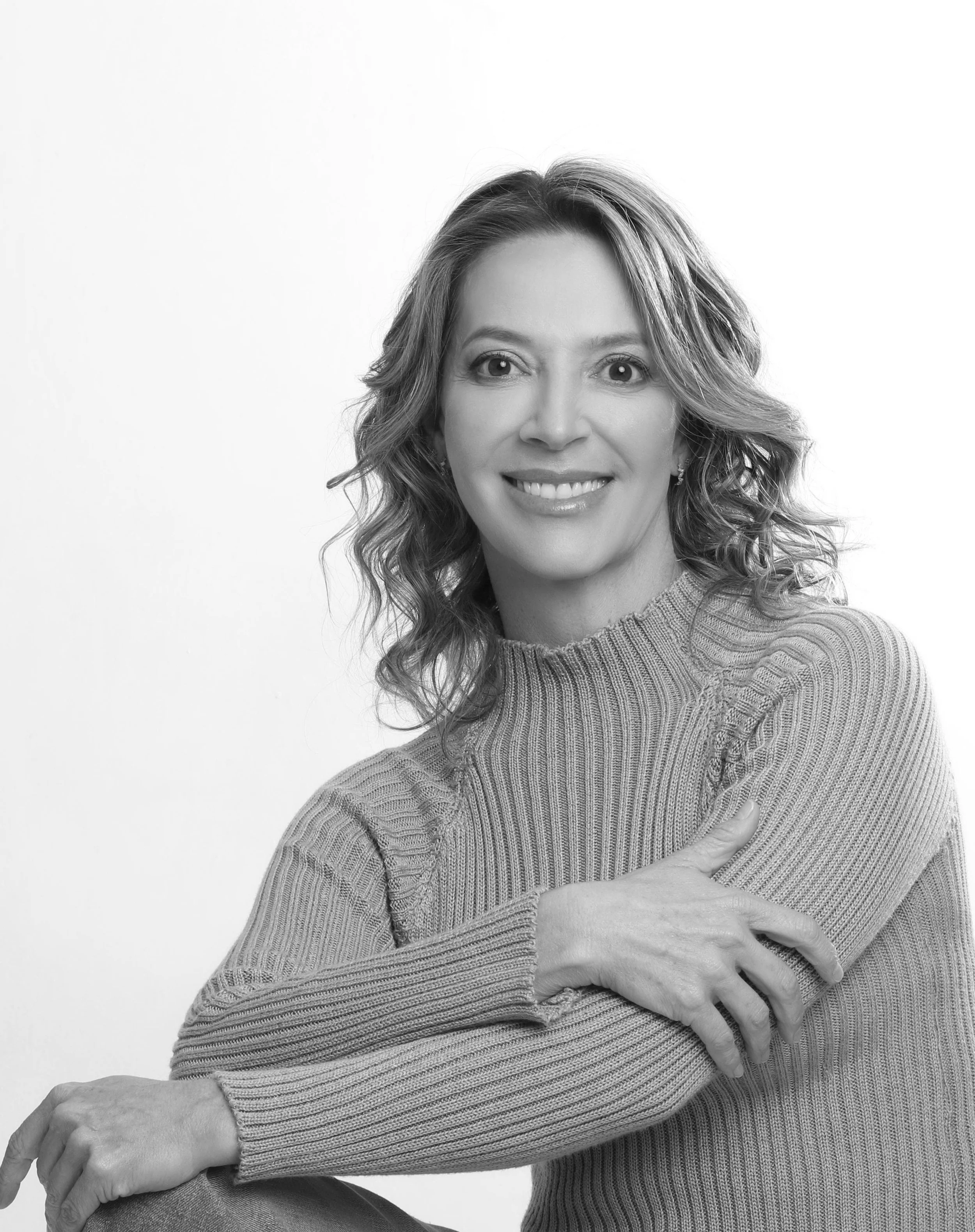 Retrato en blanco y negro de una mujer con cabello rizado, sonriendo, con un suéter de punto.