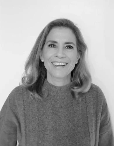 Retrato en blanco y negro de una mujer sonriendo, con pelo largo y suelto, vestida con un suéter gris.