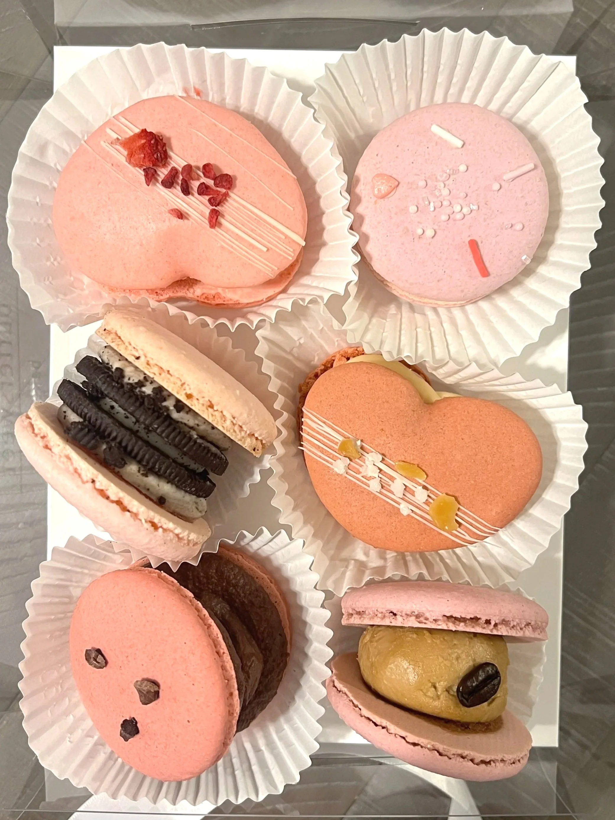 Assorted colorful macarons in various flavors and toppings on a white tray.