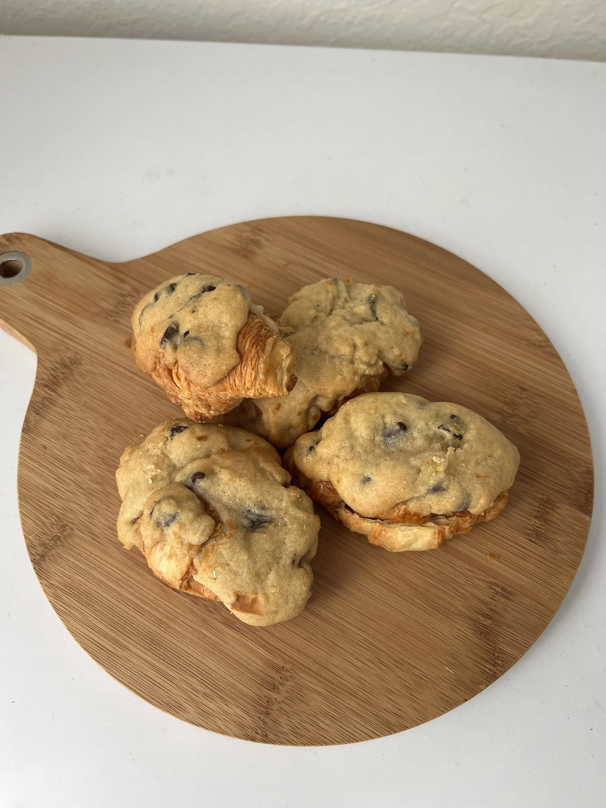 Sweet muffins with chocolate chips on a round wooden serving board.