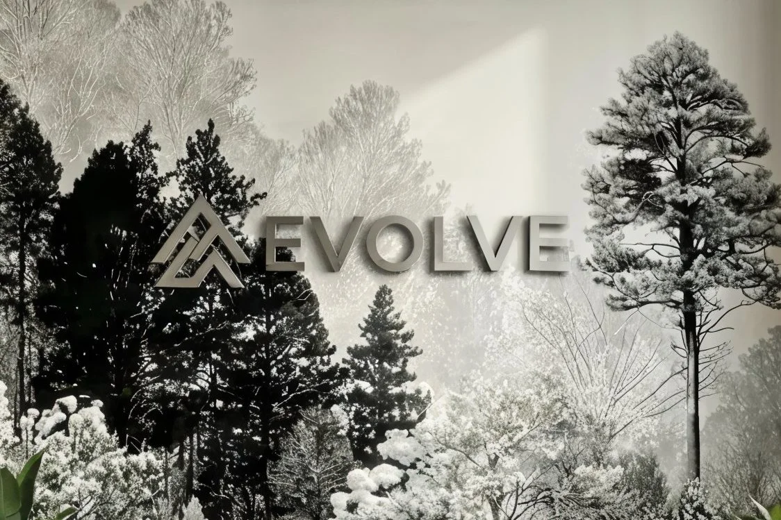 Schwarze und weiße Waldszene mit den Worten 'EVOLVE' und einem Logo aus drei Dreiecken