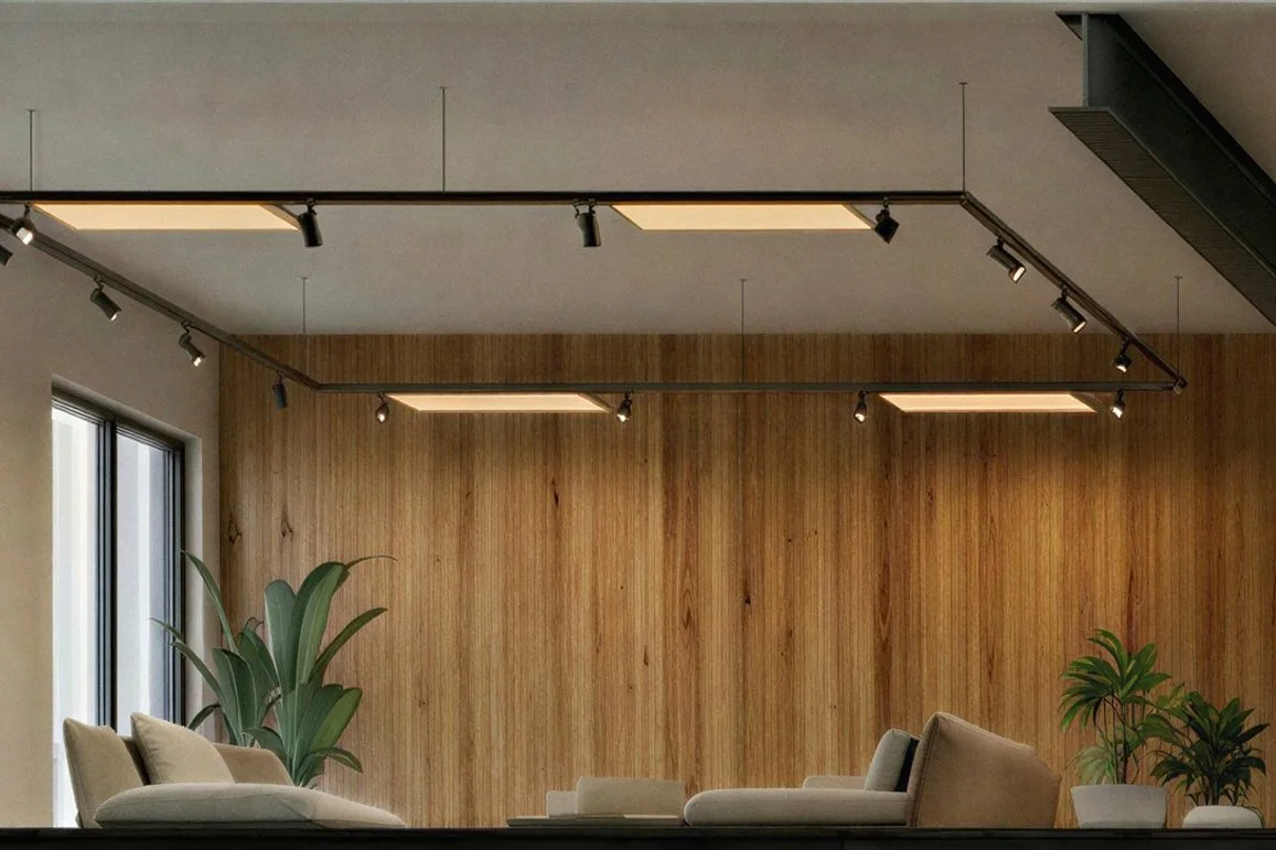 Moderner Wohnzimmerbereich mit hellem Sofa, großen Pflanzen und Holzvertäfelung an der Wand, mit Deckenlicht und großen Fenstern auf der linken Seite.