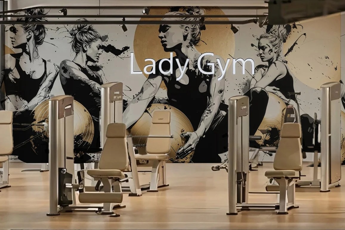 Leere Fitnessgeräte im Lady Gym mit Wandmalerei von Frauen beim Training im Hintergrund.