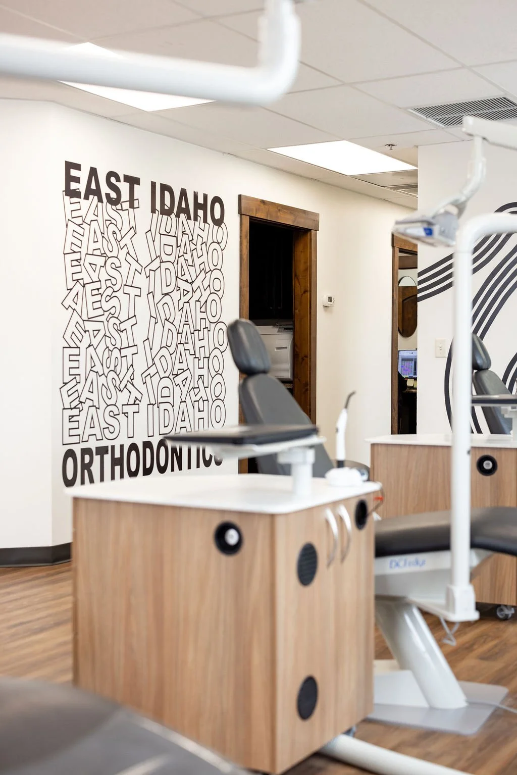 Dental treatment chairs in an orthodontic office with a wall display reading 'EAST IDAHO ORTHODONTICS'.