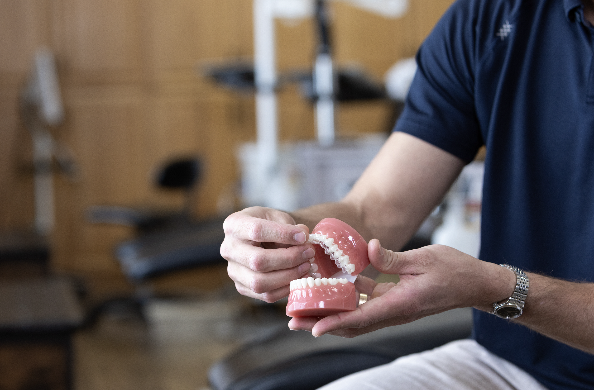 Person holding a set of dental practice dentures, demonstrating the upper and lower teeth.