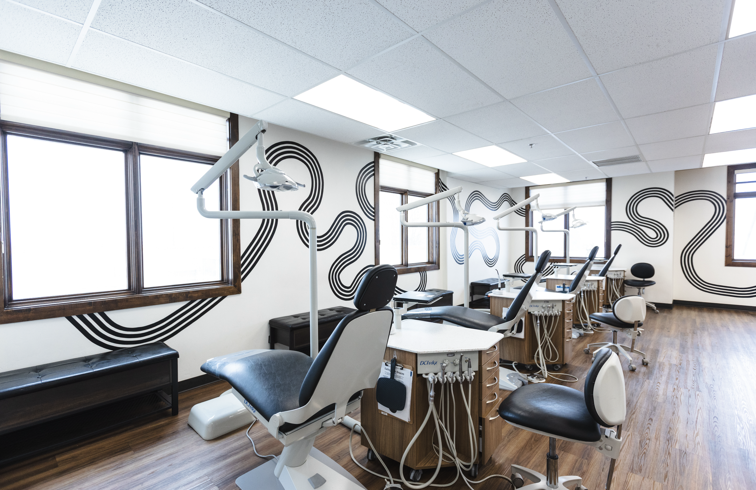 Dental treatment rooms with dental chairs, equipment, and black wall art design.