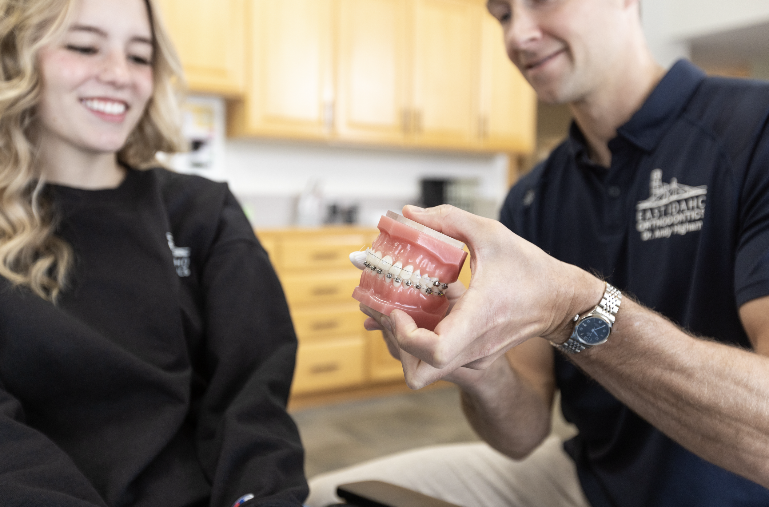Orthodontist showing a model of teeth with damon braces to a young female patient in Idaho Falls.