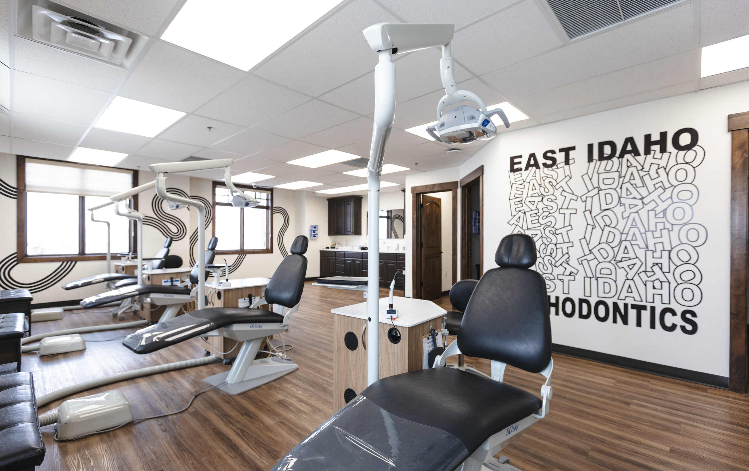 Interior of a dental office with dental chairs, equipment, and a wall with text reading "East Idaho Orthodontics."