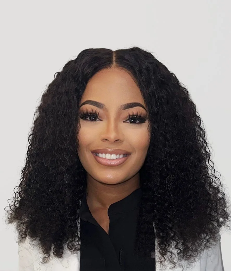 A woman with curly black hair, makeup, and a bright smile.