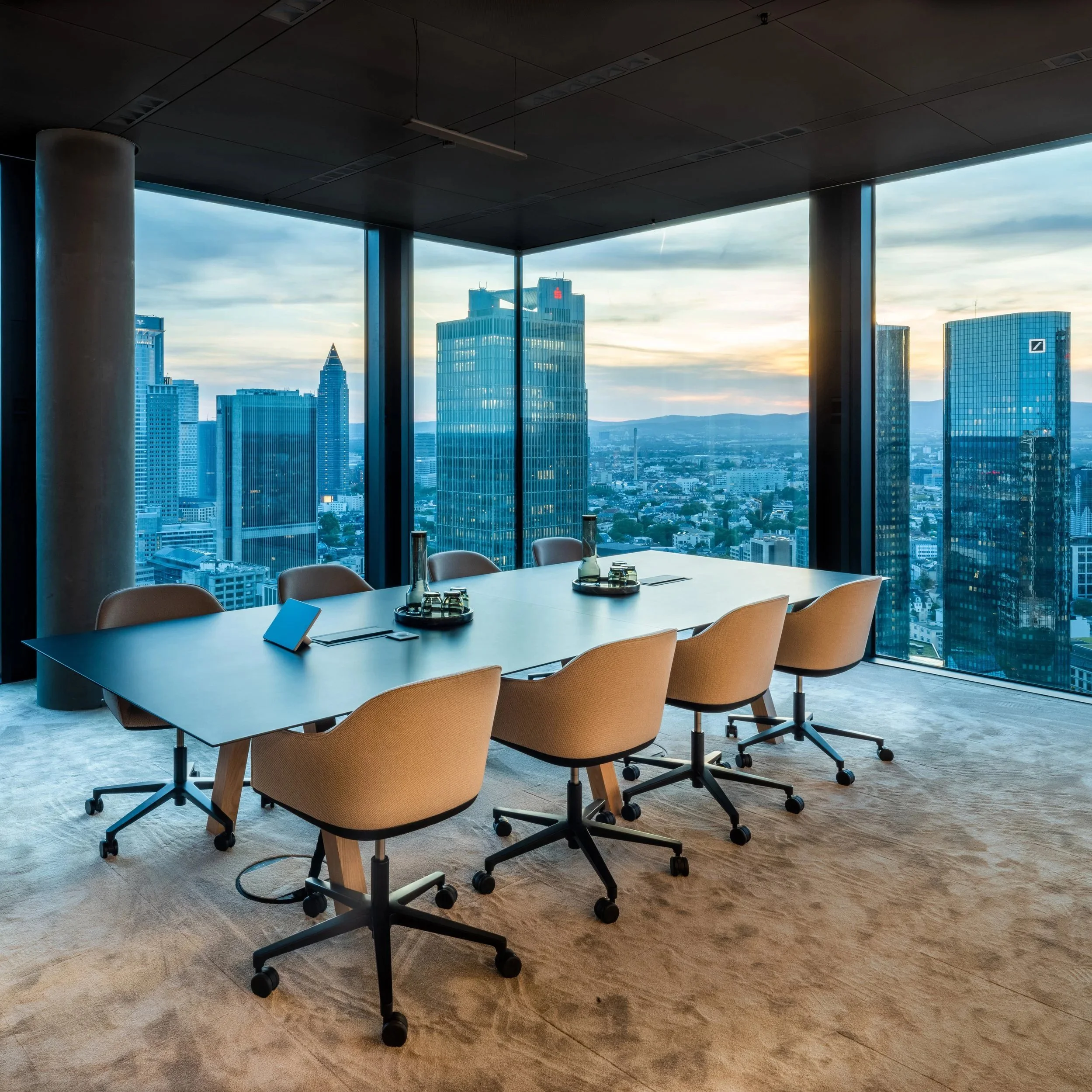 Konferenzraum mit beigen Bürostühlen und Panorama-Skyline bei Sonnenuntergang – Innenarchitektur