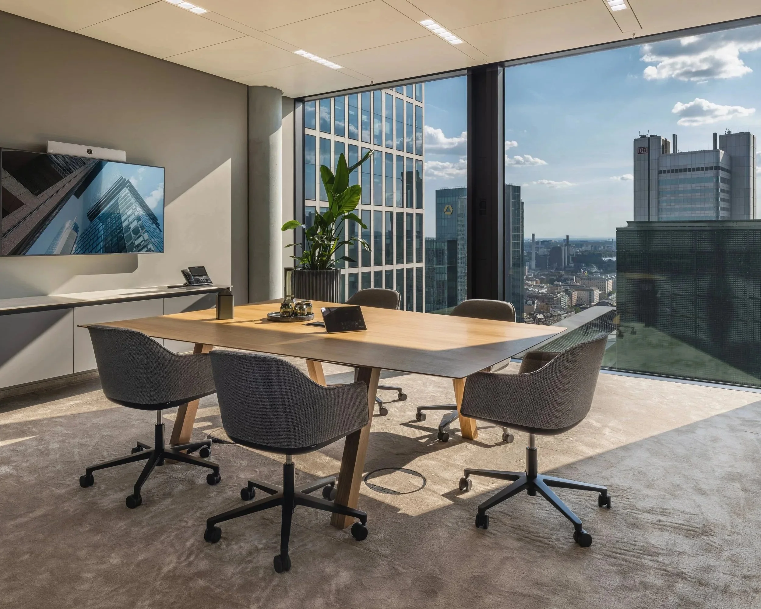 Konferenzraum mit Holztisch, grauen Drehstühlen und Panoramafenstern – Innenarchitektur für Büroräume