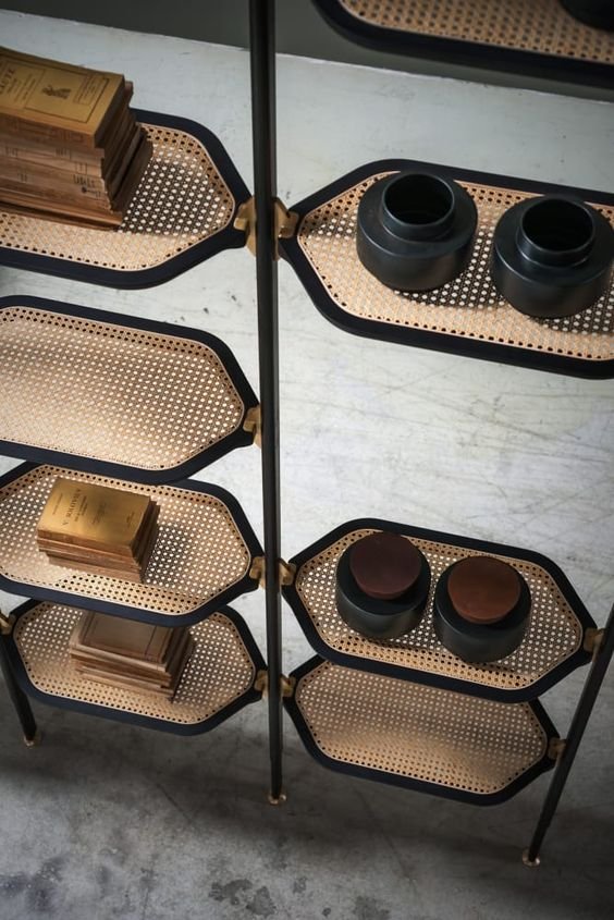 Regal aus schwarzem Metall und Rattan mit Büchern und Vasen – Innenarchitektur
