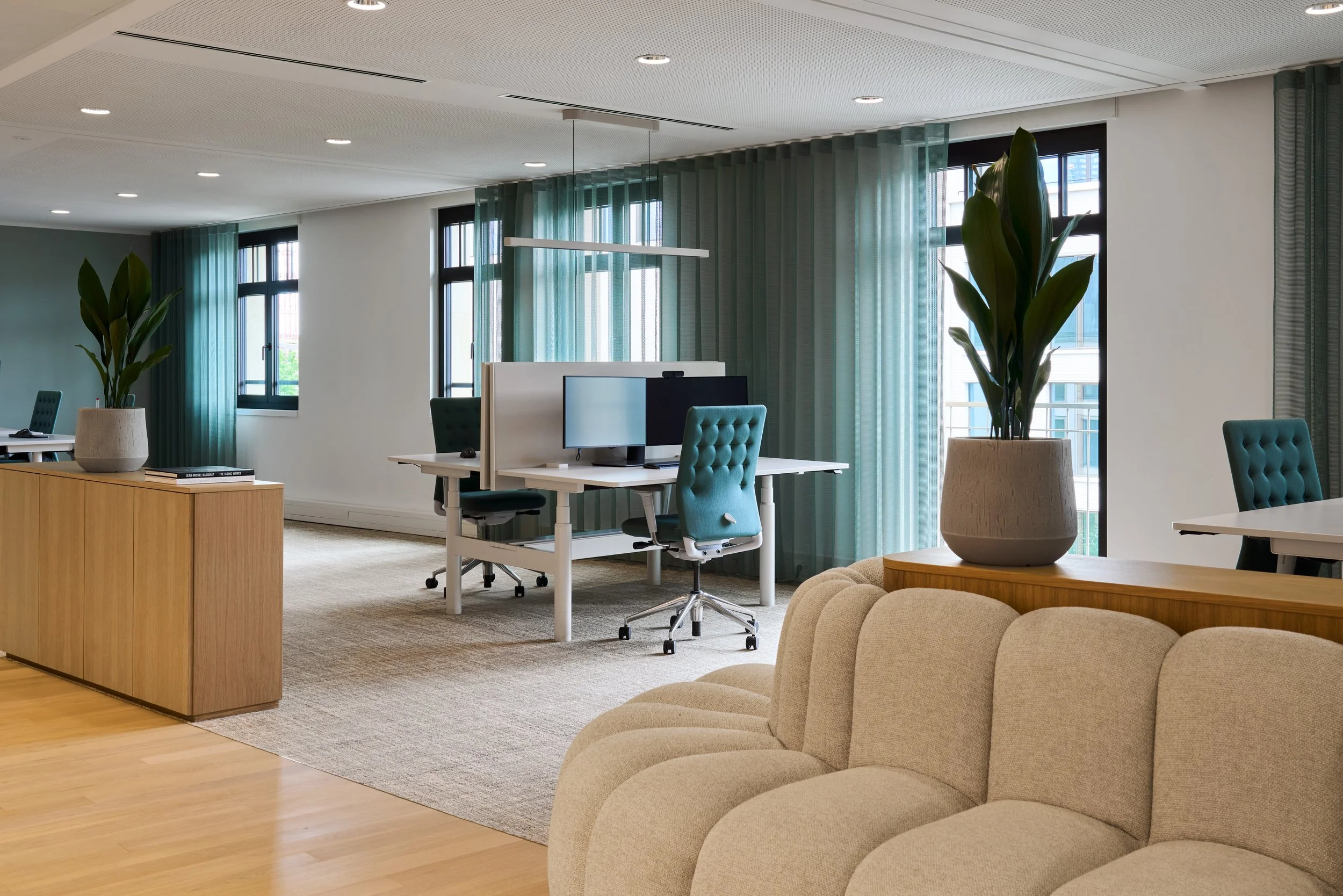 Moderne Bürofläche mit Loungebereich, beigem Sofa und Panoramafenstern – Innenarchitektur für Büroräume