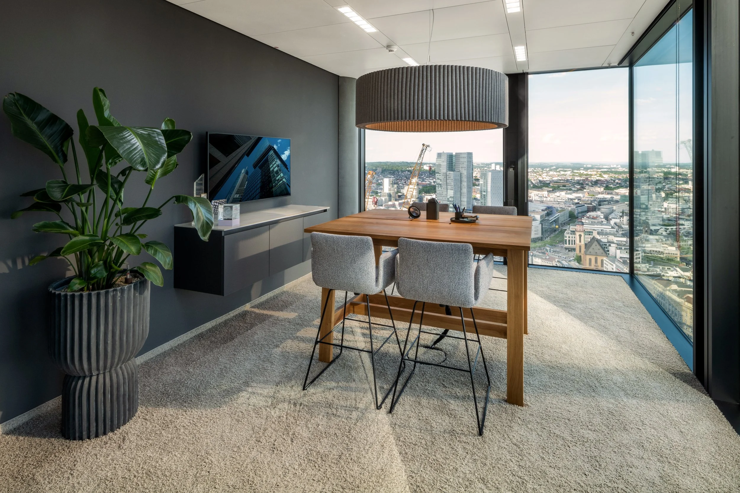 Konferenzraum mit Holztisch, runder Pendelleuchte und Skyline-Blick – Innenarchitektur für Büroräume