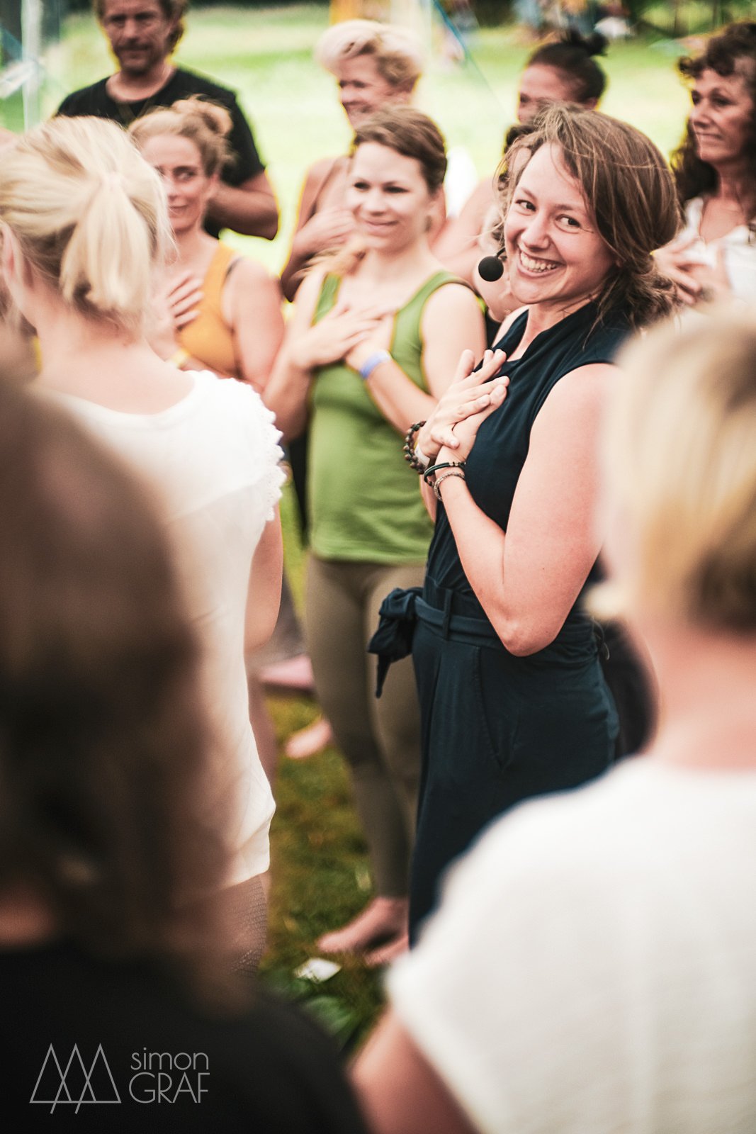 Menschen beim Yoga im Freien, alle halten ihre Hände auf das Herz, ein lachende Marina Inara im Mittelpunkt.