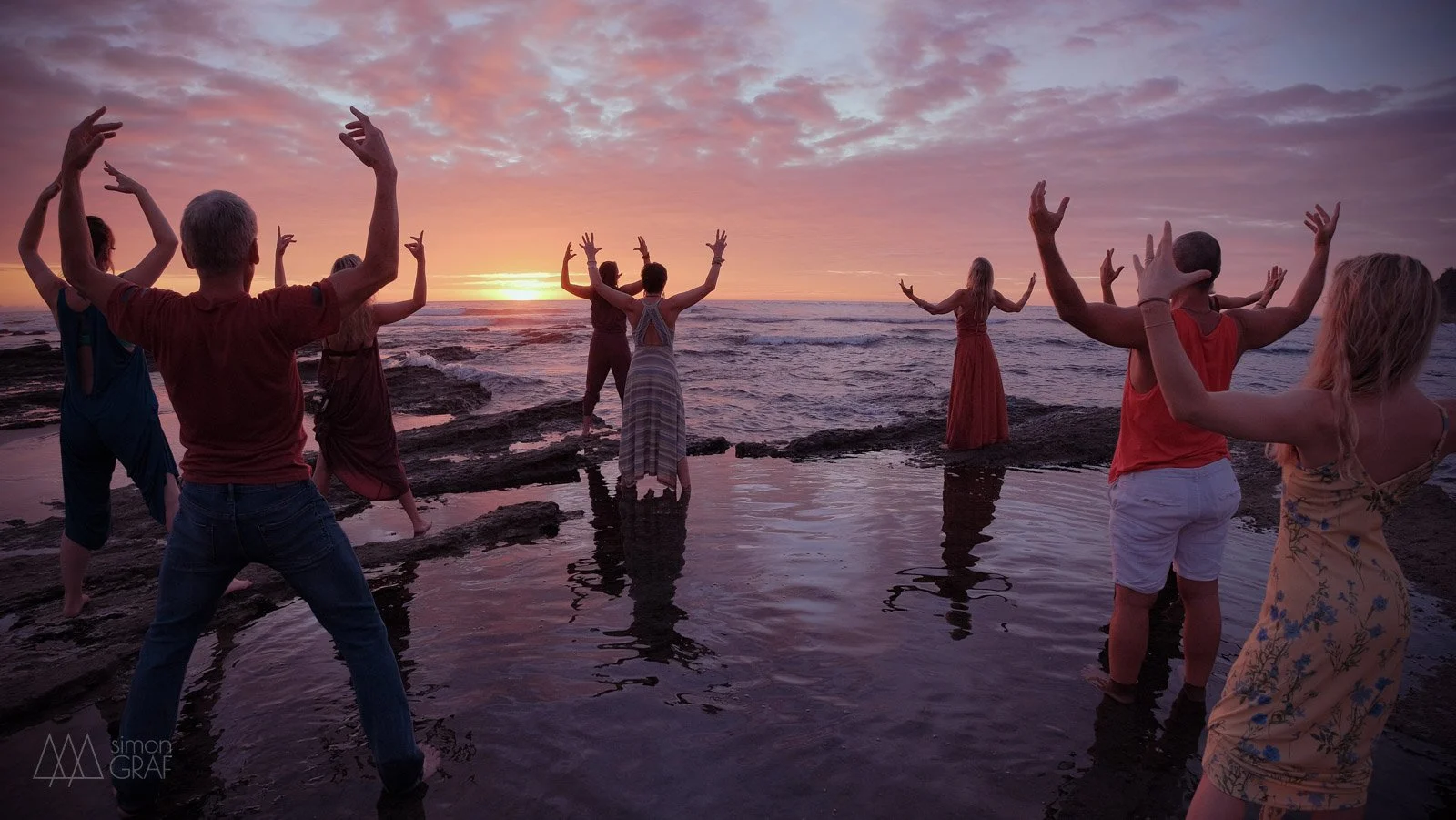 Menschen tanzen am Strand bei Sonnenuntergang