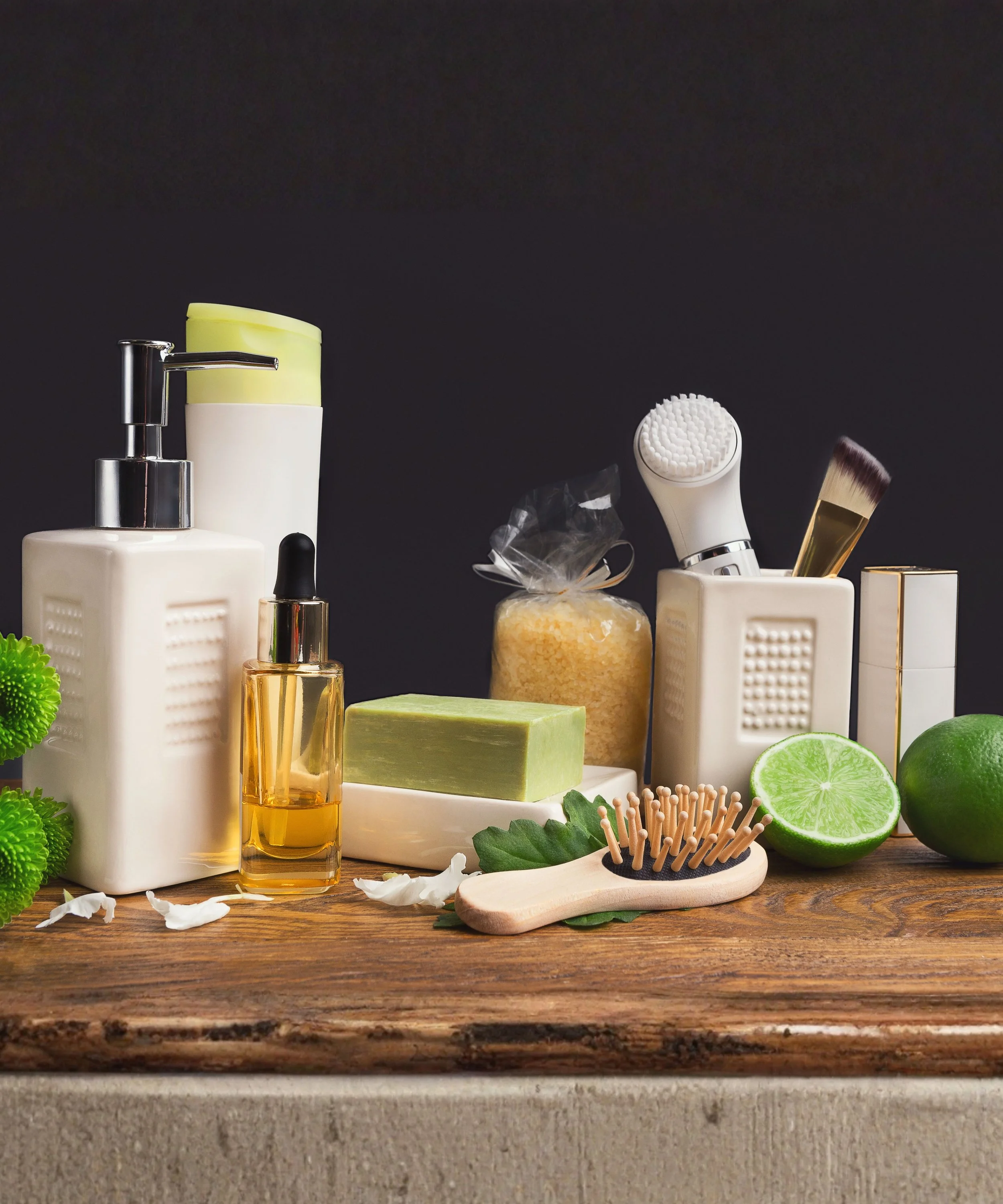 Bathroom skincare and grooming products including brushes, soap, lotion, lime, and bath salts on a wooden surface.