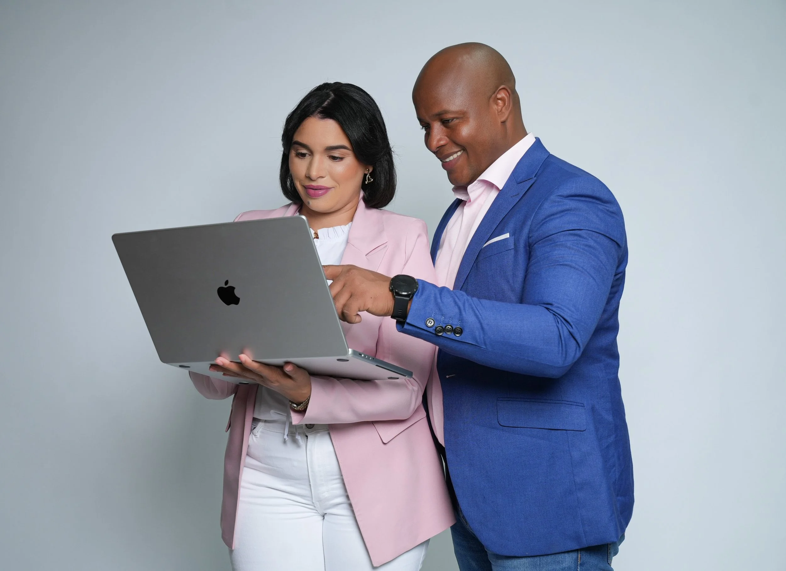 Hombre y mujer de negocios mirando una computadora portátil juntos, con fondo gris