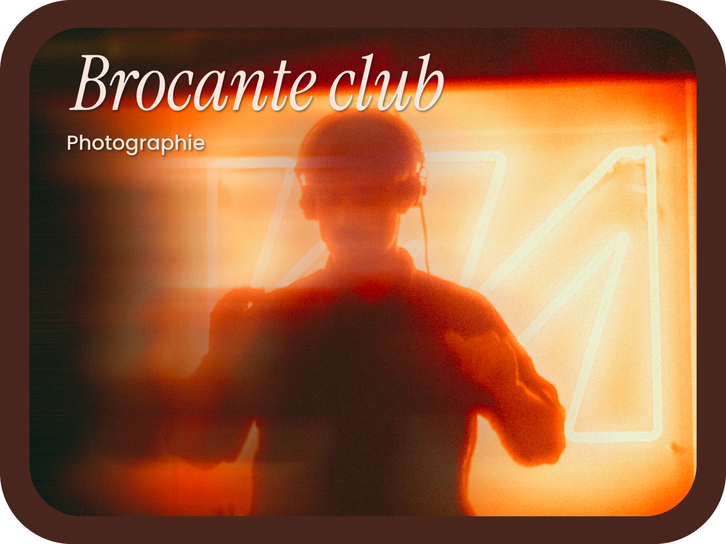 A person wearing glasses and headphones taking a selfie in front of a neon sign background with the text "Brocante club" and "Photographie".