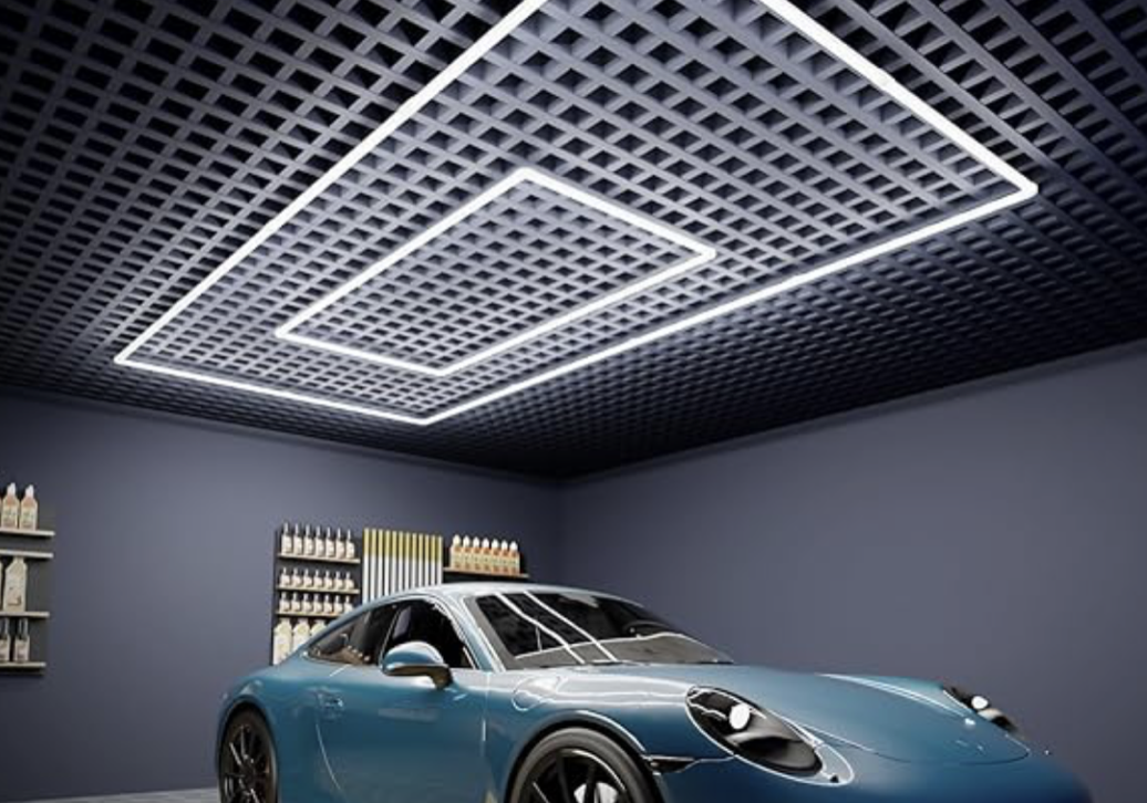 A modern blue sports car parked in a gray garage with dark walls and an intricate ceiling design featuring LED light fixtures.