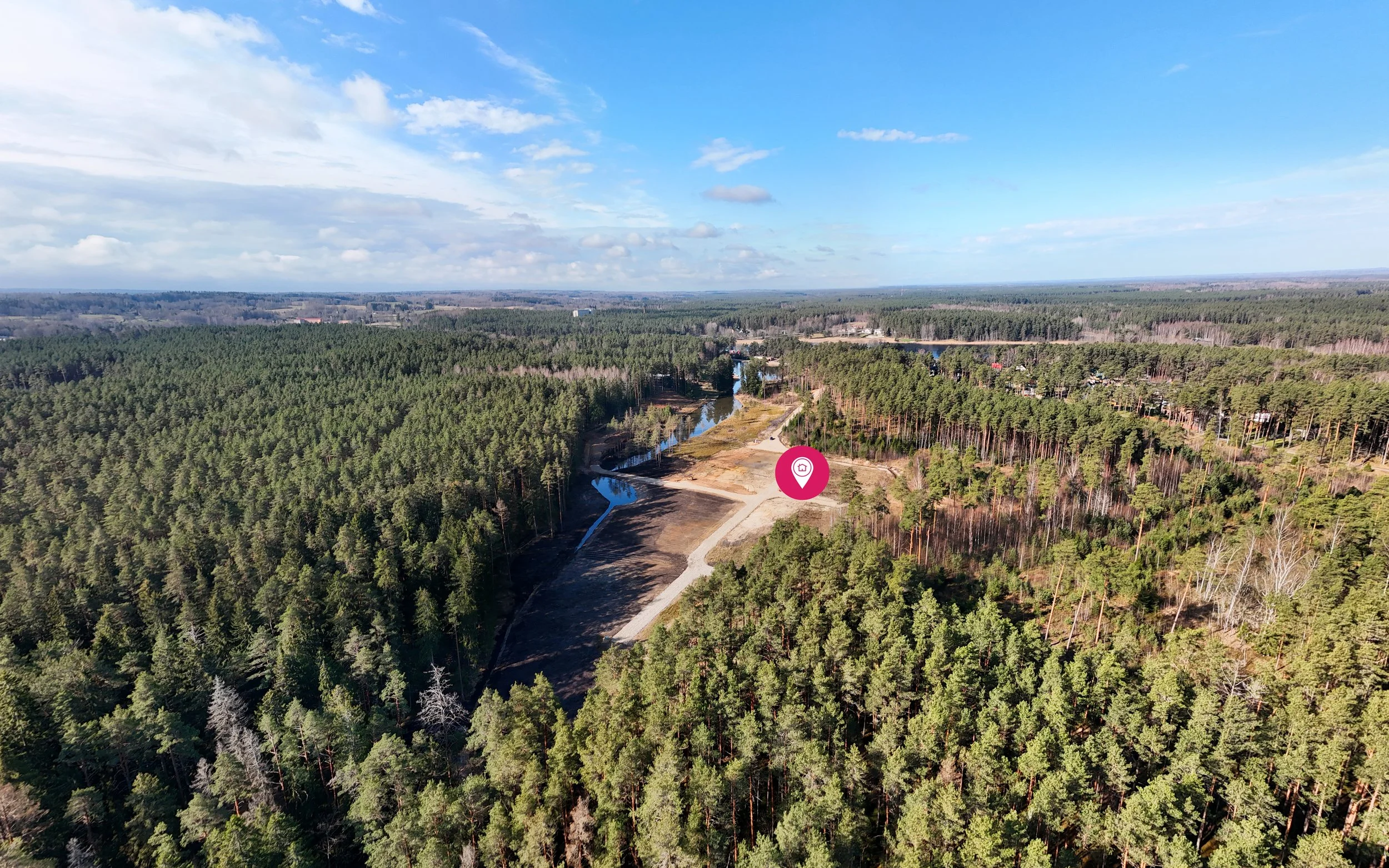 Aerial view of a forested landscape with a river running through it, under a partly cloudy sky.