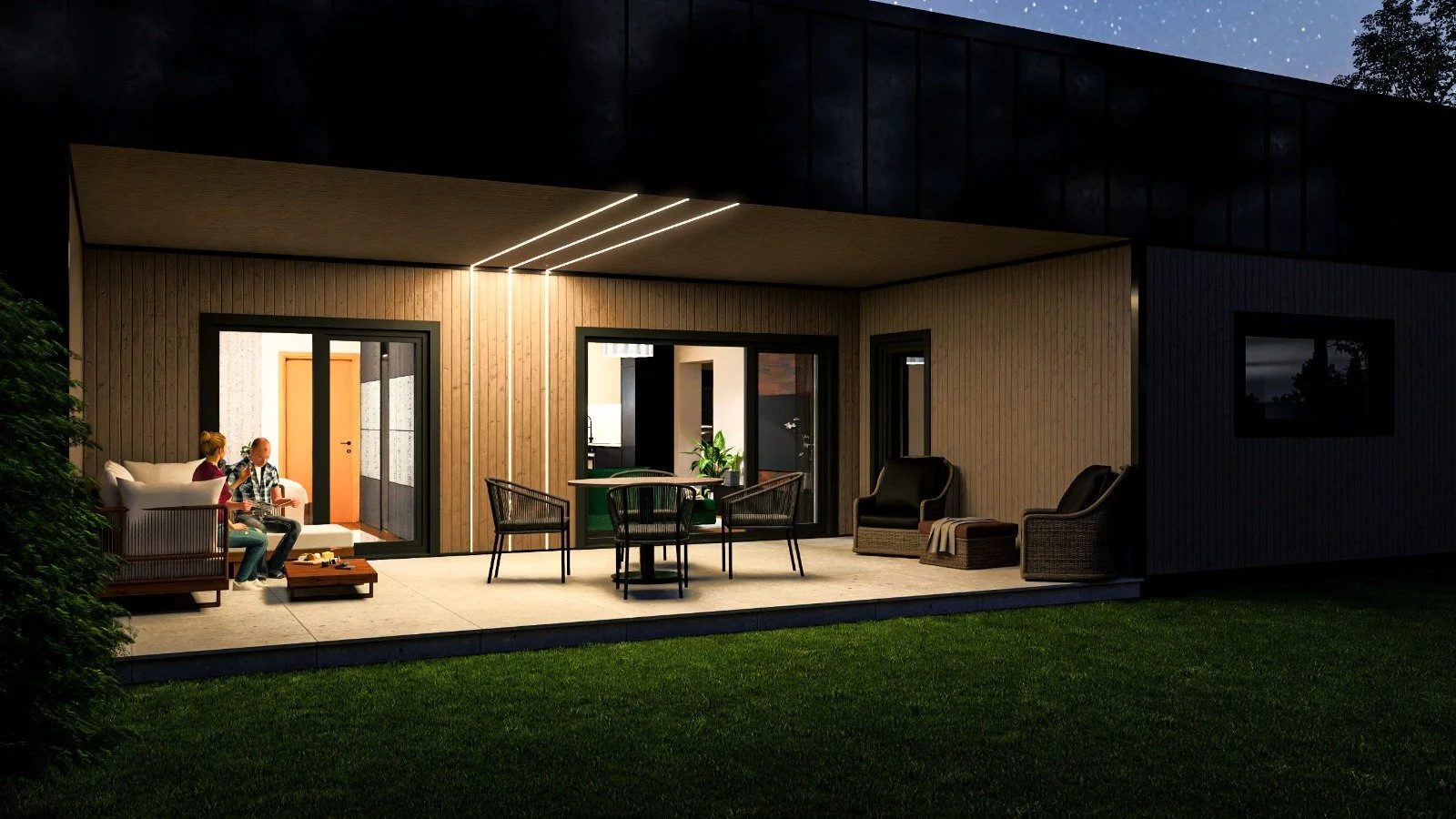 Night view of a modern house outdoor patio with wicker chairs, a round table, a cushioned bench, and two women sitting and talking, illuminated by ceiling lights, with the house interior visible through sliding glass doors.