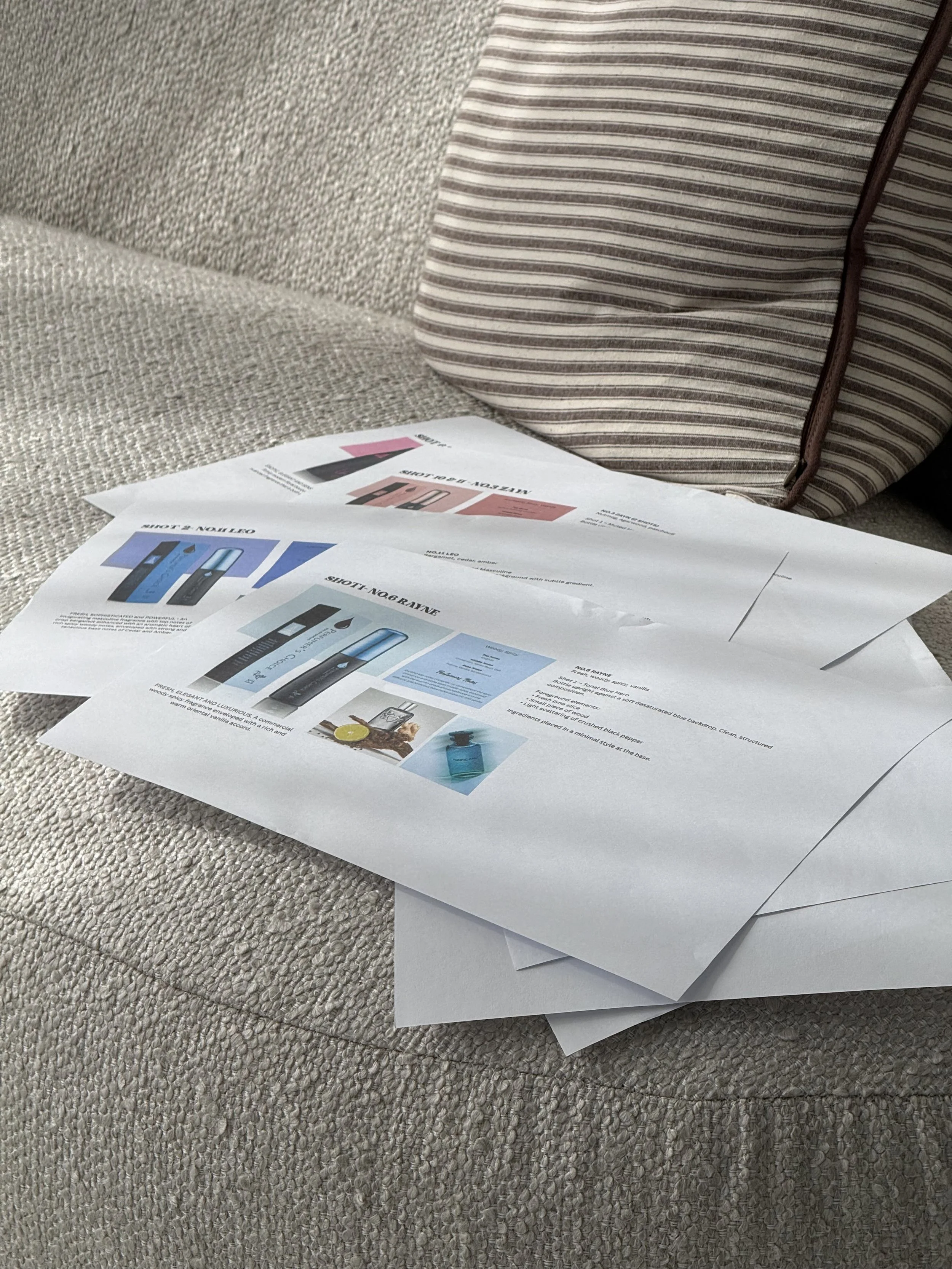 Several paper flyers or advertisements placed on a beige couch with a striped bag in the background.