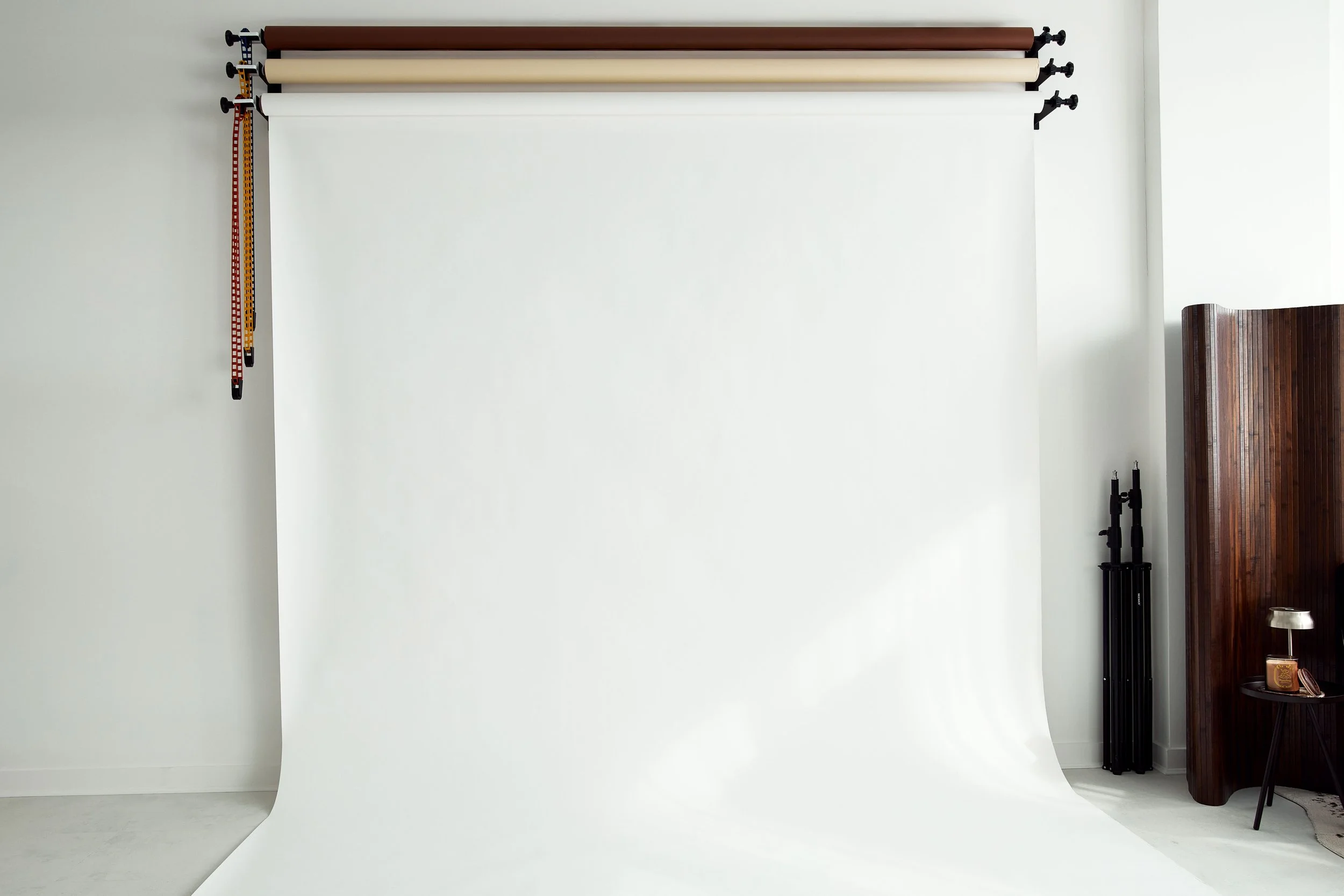 Photography backdrop setup with paper rolls and stand in a minimal studio