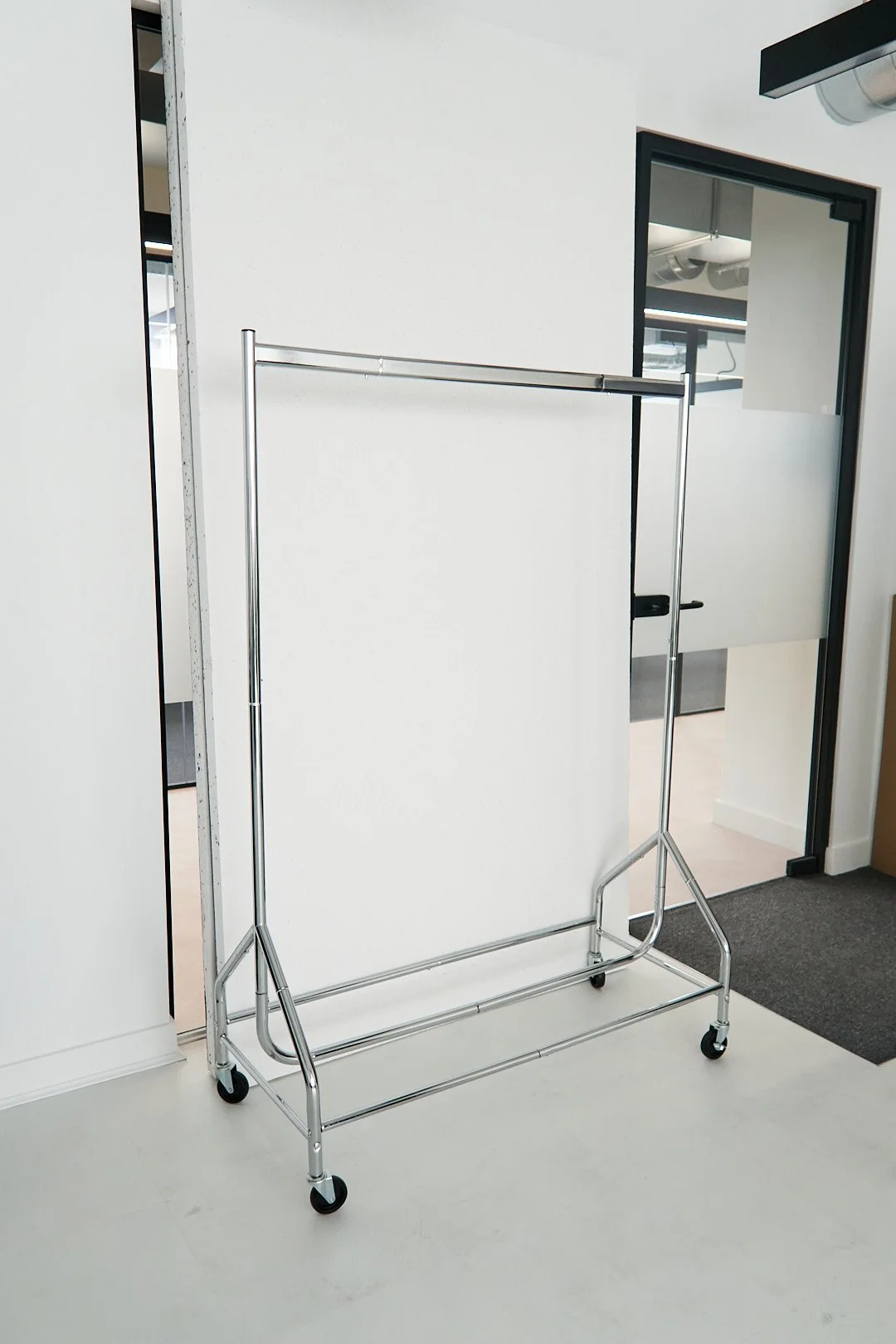 Empty metal clothing rack on casters in an office space.
