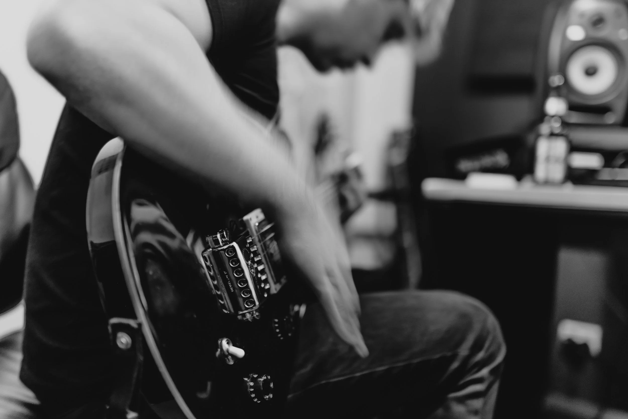 A person adjusting settings on an audio mixer or soundboard in a studio or performance space, with speakers in the background.