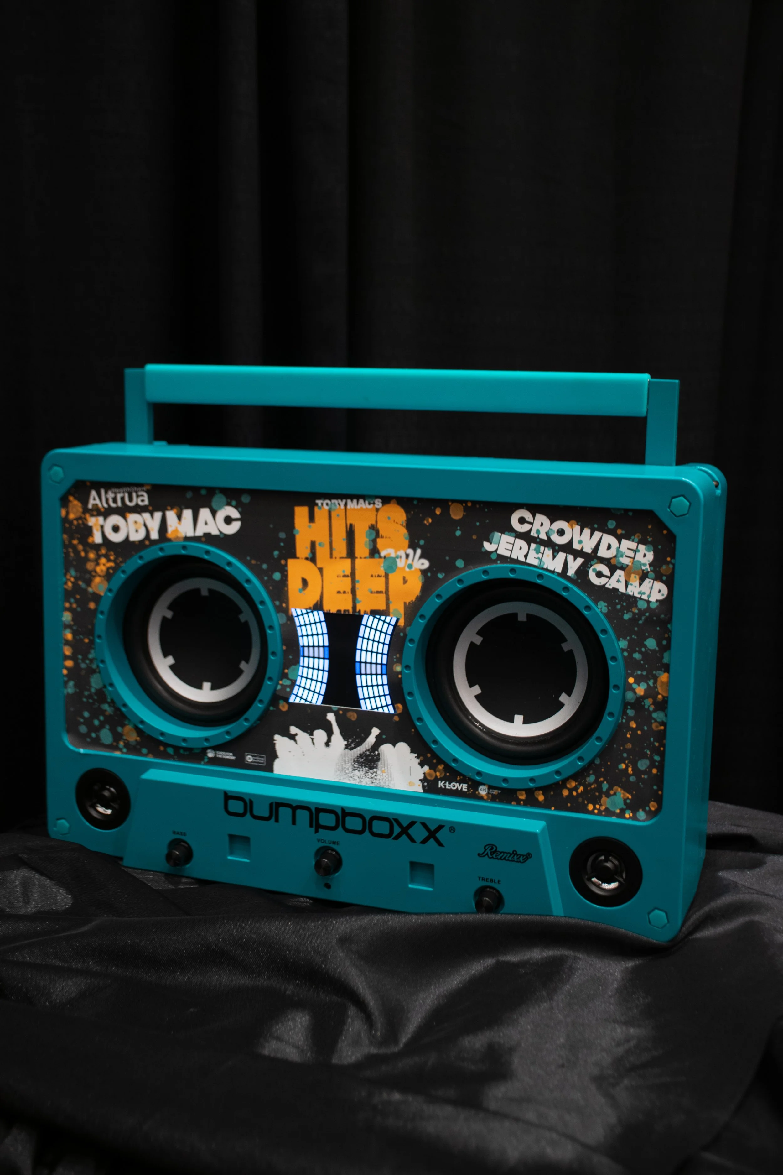 A blue Boombox with a digital display, speakers, and control buttons, set against a black background.
