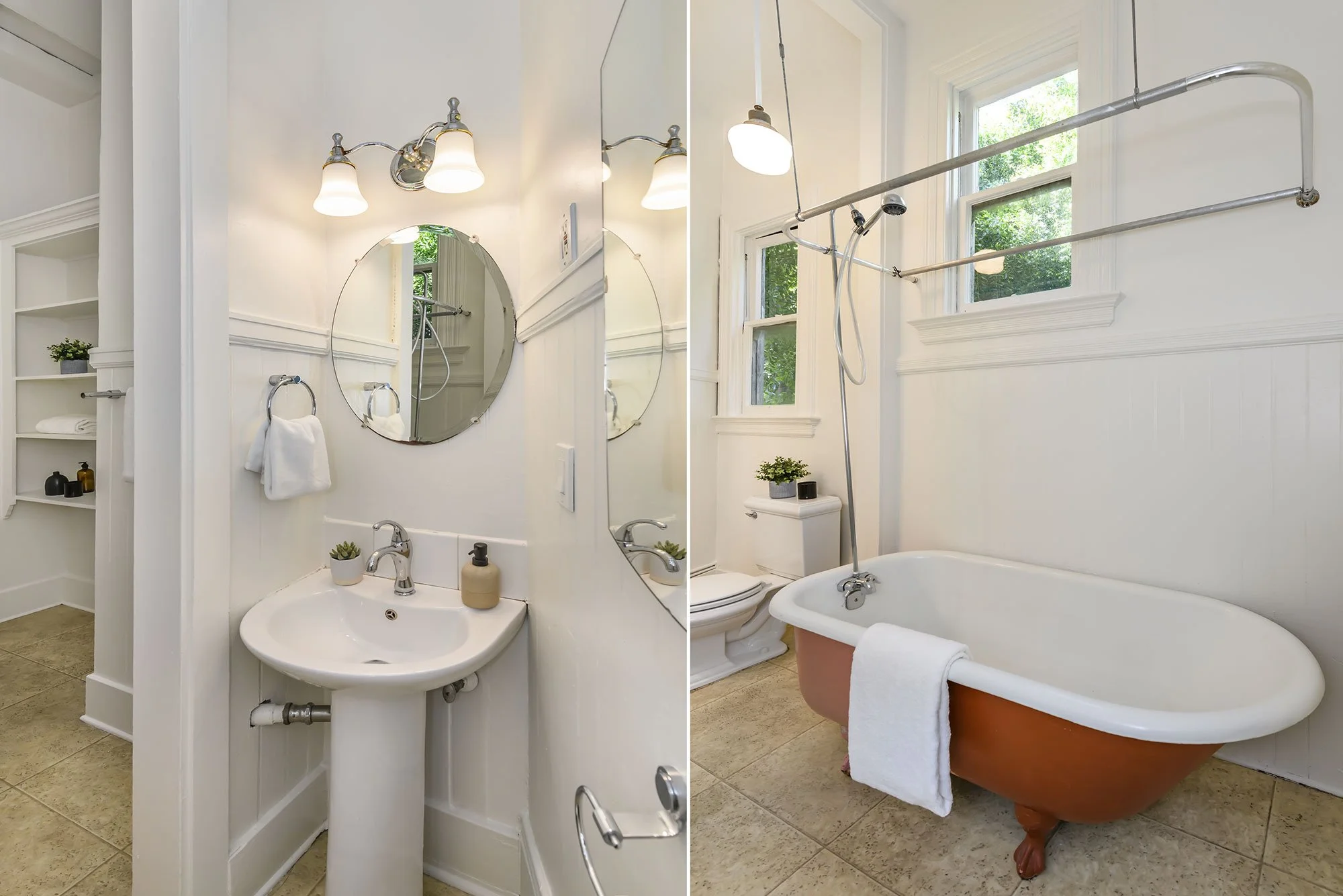 Bathroom with a pedestal sink and a mirror, two wall-mounted lamps, towel rings, an open shelving unit, and toiletries; separate bathtub with clawfoot design, a towel, small potted plant, and two windows with green trees outside.