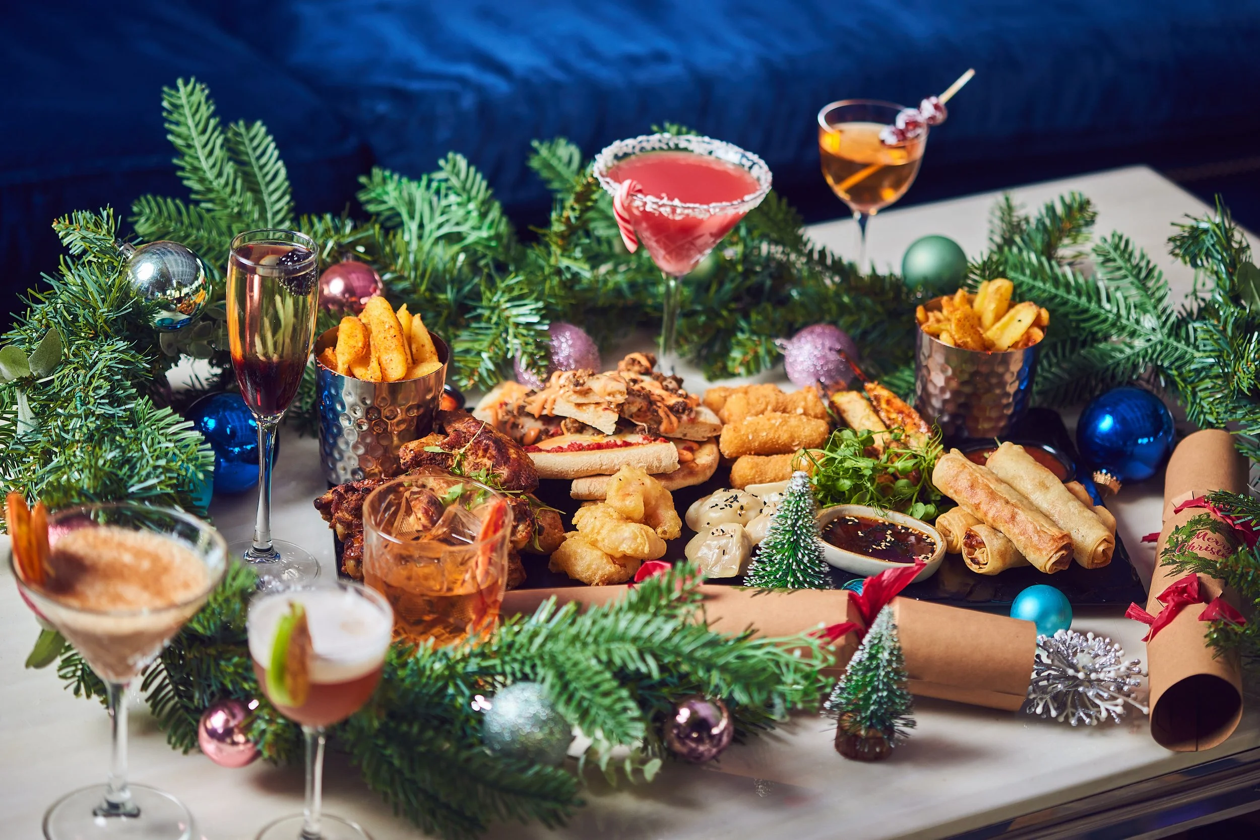 Festive holiday table with assorted appetizers, drinks, and Christmas decorations.