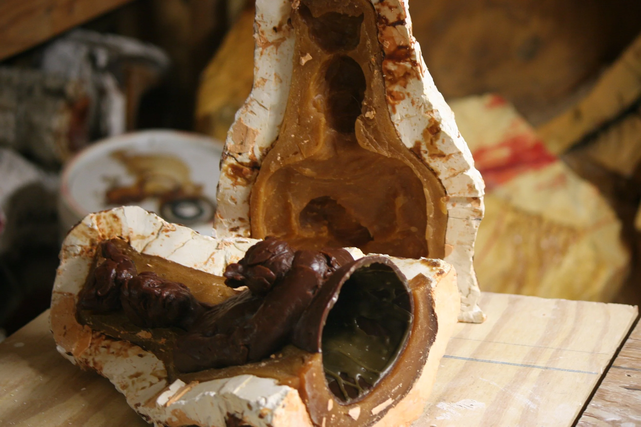 Close-up of a sliced rubber and plaster mold with a wax sculpture inside.