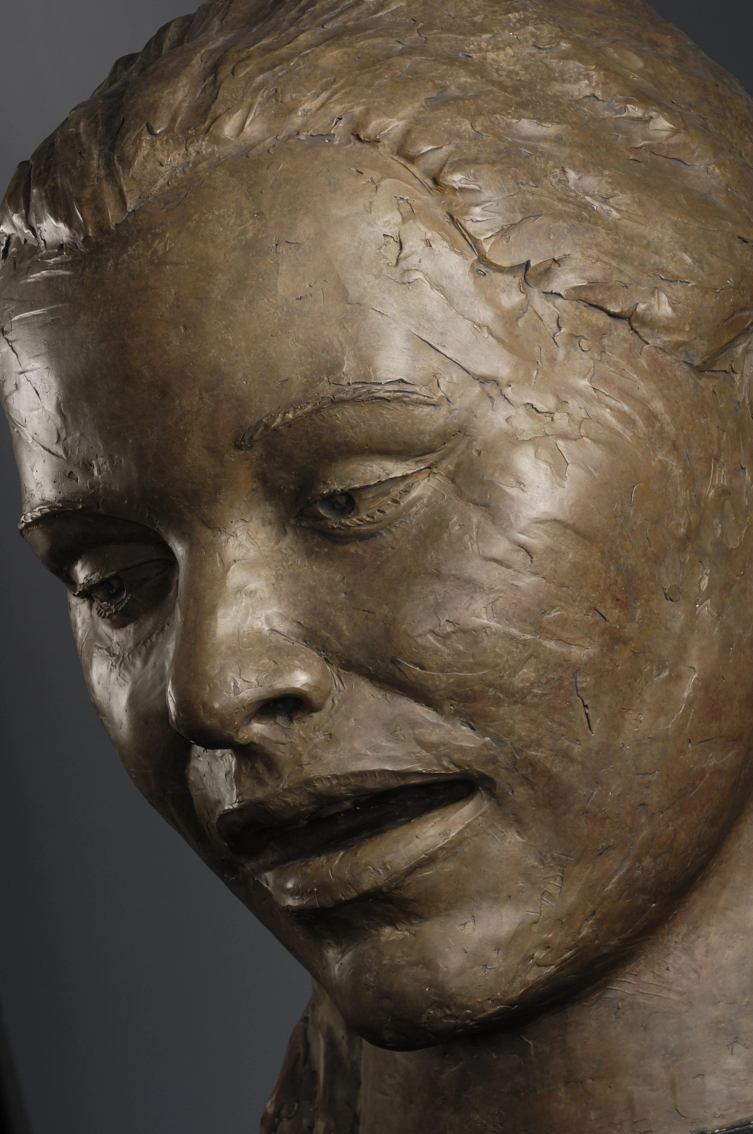Close-up of a bronze sculpture depicting a human face with closed eyes and serene expression.  Cultural Heroes