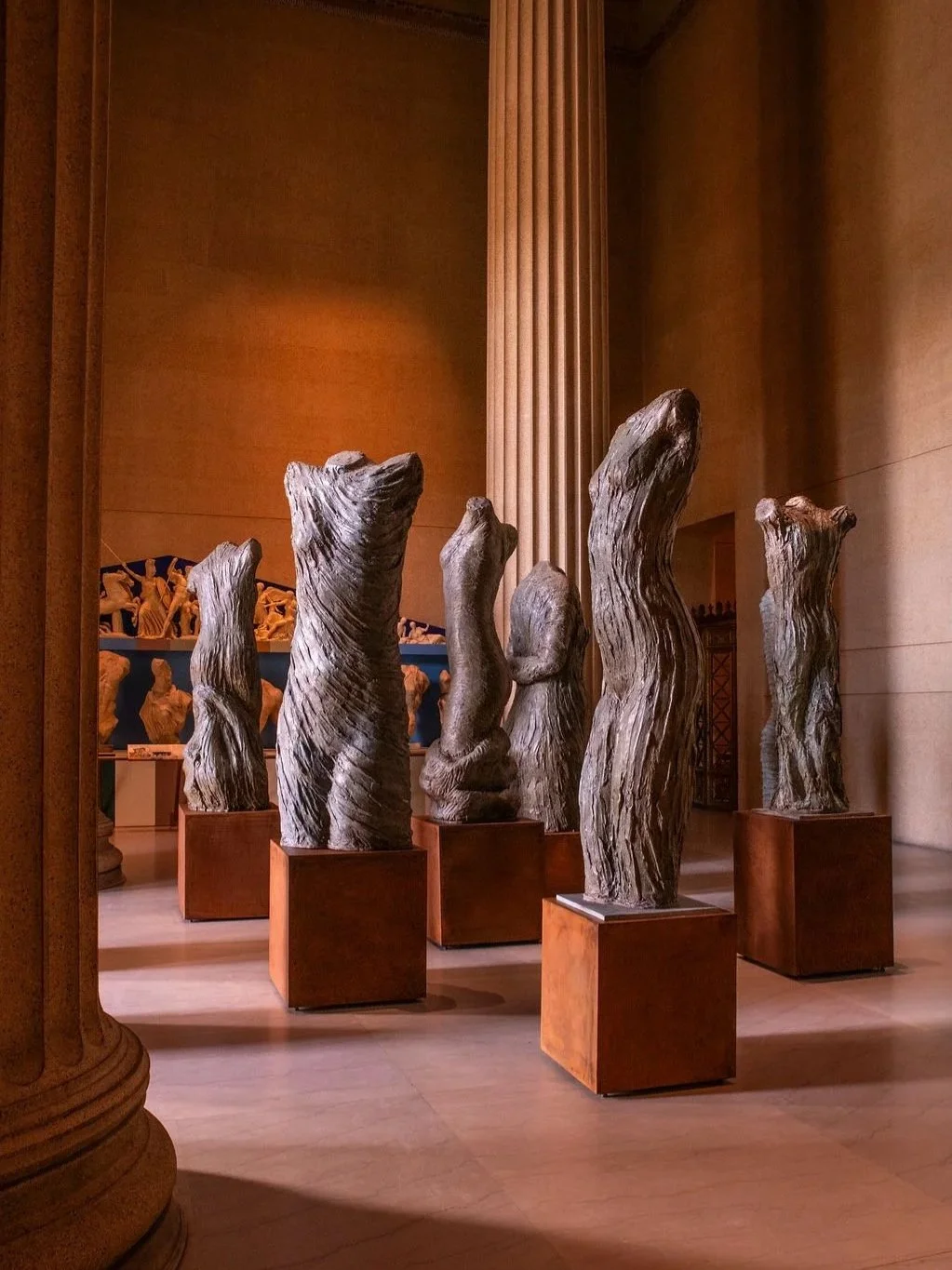 Indoor display of multiple sculptures on individual stands in a museum or gallery. At the Parthenon Museum.