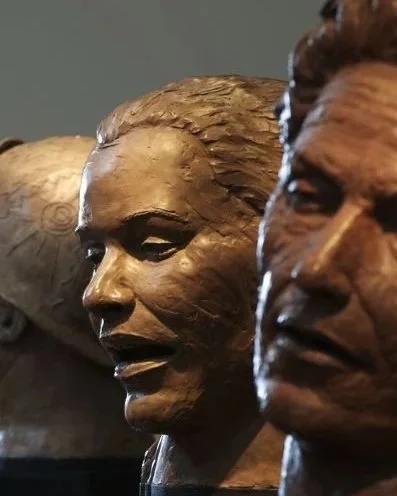 Close-up of three bronze bust sculptures of human faces.  Cultural Heroes
